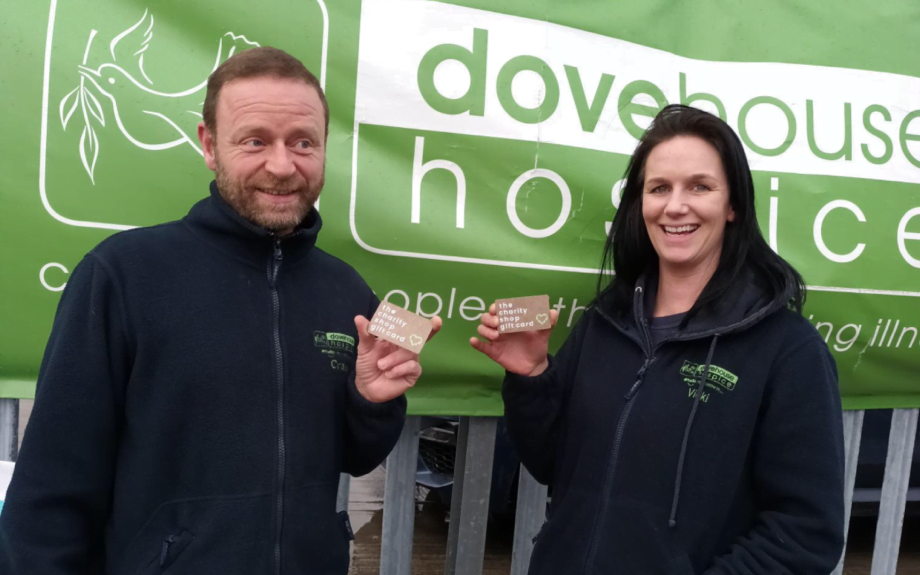 Craig and Vicki of Dove Hopsice hold up The Charity Shop Gift Card